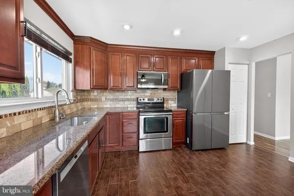 a kitchen with granite countertop a refrigerator stove top oven and sink