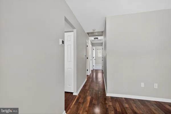 a view of a hallway with wooden floor and a bathroom