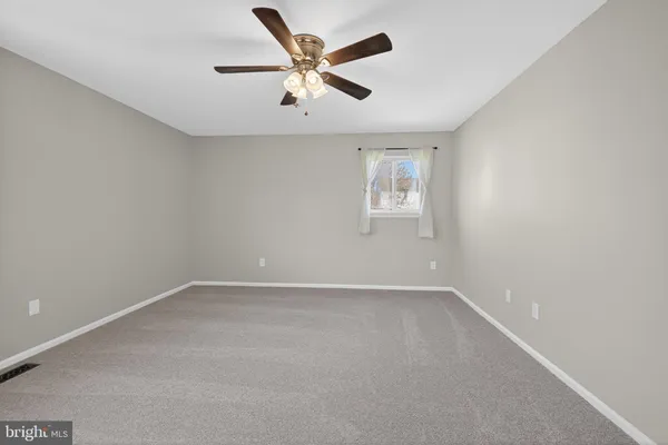 an empty room with a window and ceiling fan