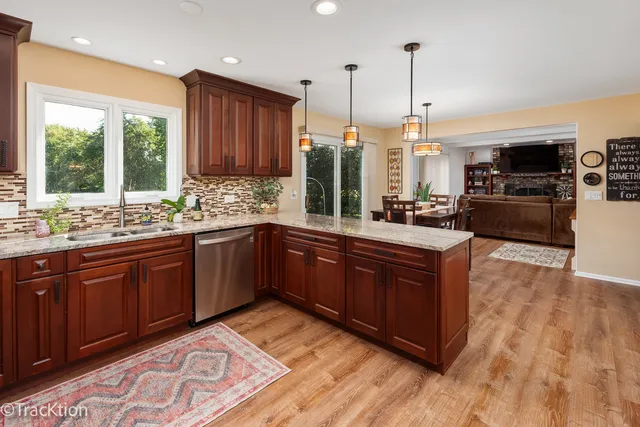 a kitchen with stainless steel appliances granite countertop wooden cabinets a stove a sink and a large window