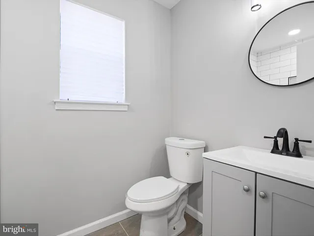 a bathroom with a toilet sink vanity and mirror