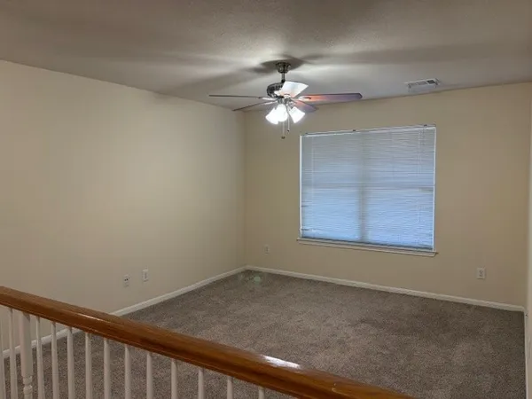 an empty room with a chandelier fan and windows