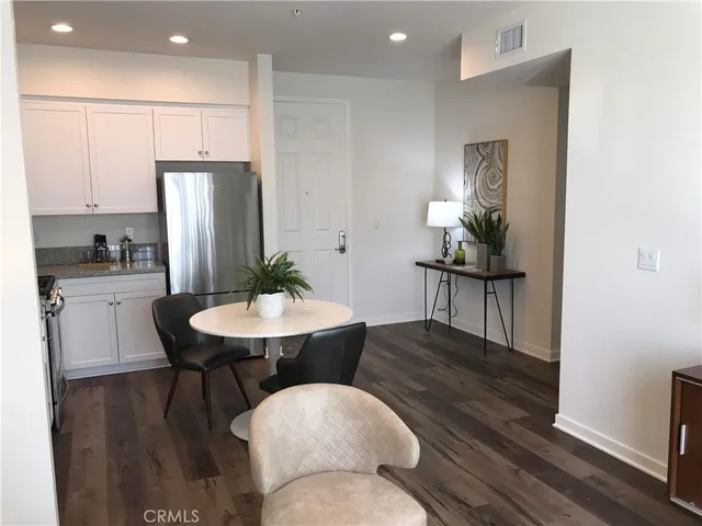 a kitchen with stainless steel appliances a dining table chairs and refrigerator