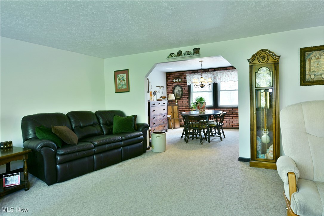 379 Housel Craft Road Bristolville, OH 44402 - Photo 20 of 50 Carpeted living room with an inviting chandelier, arched walkways, and a textured ceiling