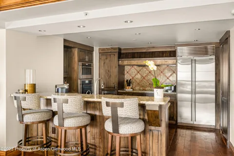 a kitchen with stainless steel appliances a dining table chairs and a large window