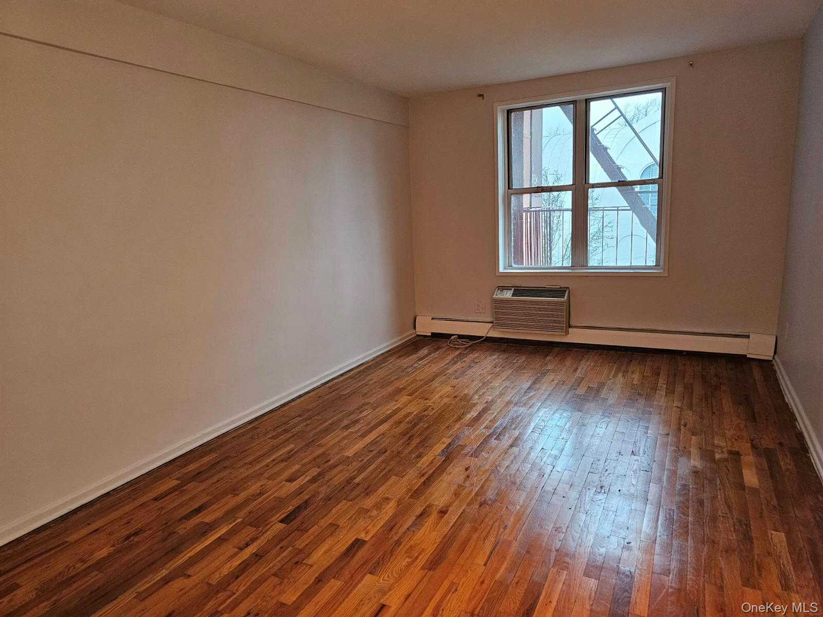 151-05 Cross Island Parkway, Unit 3E Queens, NY 11357 - Photo 13 of 29 an empty room with wooden floor and windows