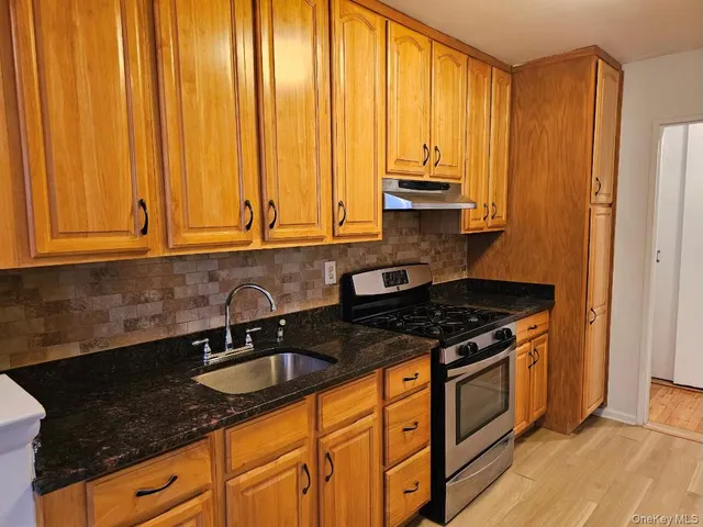 a kitchen with granite countertop a sink a stove and cabinets