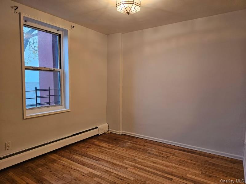 151-05 Cross Island Parkway, Unit 3E Queens, NY 11357 - Photo 9 of 29 a view of an empty room with wooden floor and a window