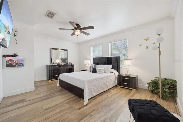 a spacious bedroom with a bed lamp and a potted plant