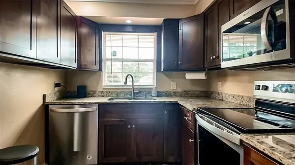 a kitchen with stainless steel appliances granite countertop a sink a stove a microwave cabinets and a window