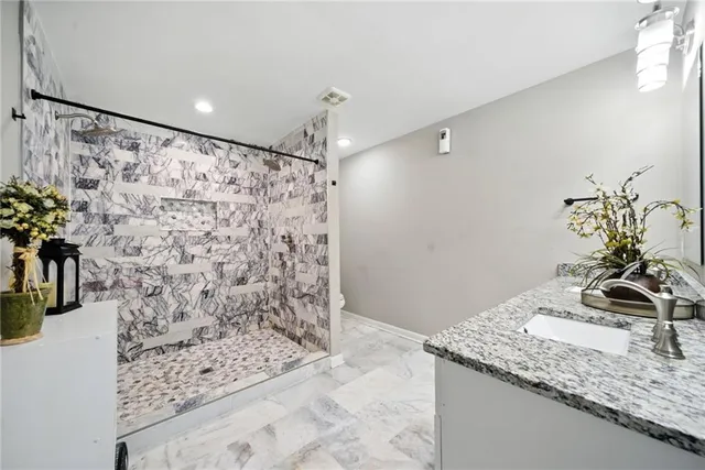 a bathroom with a granite countertop sink a mirror and shower