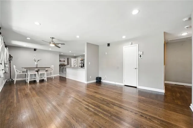 an empty room with wooden floor and a kitchen