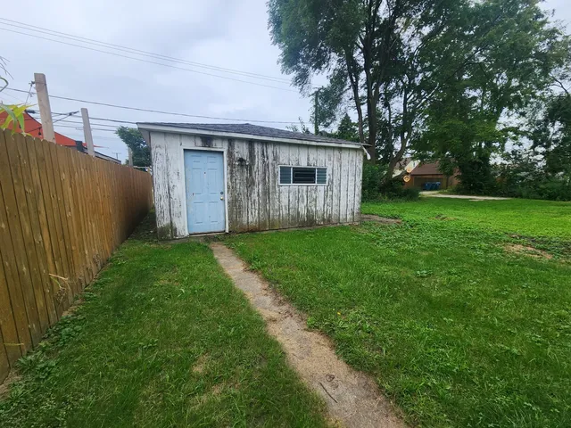 a view of a small house with a big yard and large trees