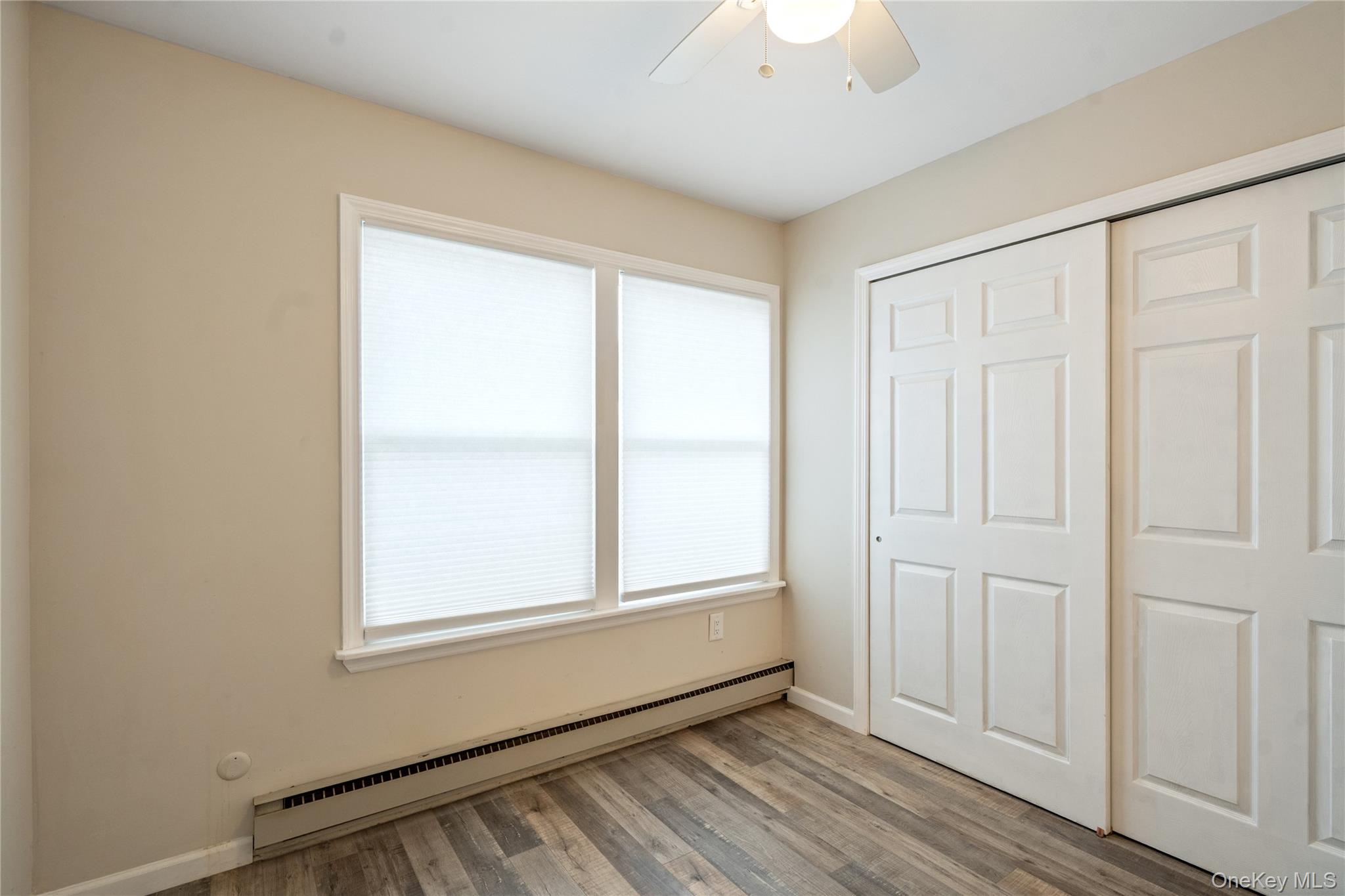 53 Freedom Lane Coram, NY 11784 - Photo 12 of 29 an empty room with wooden floor closet and windows