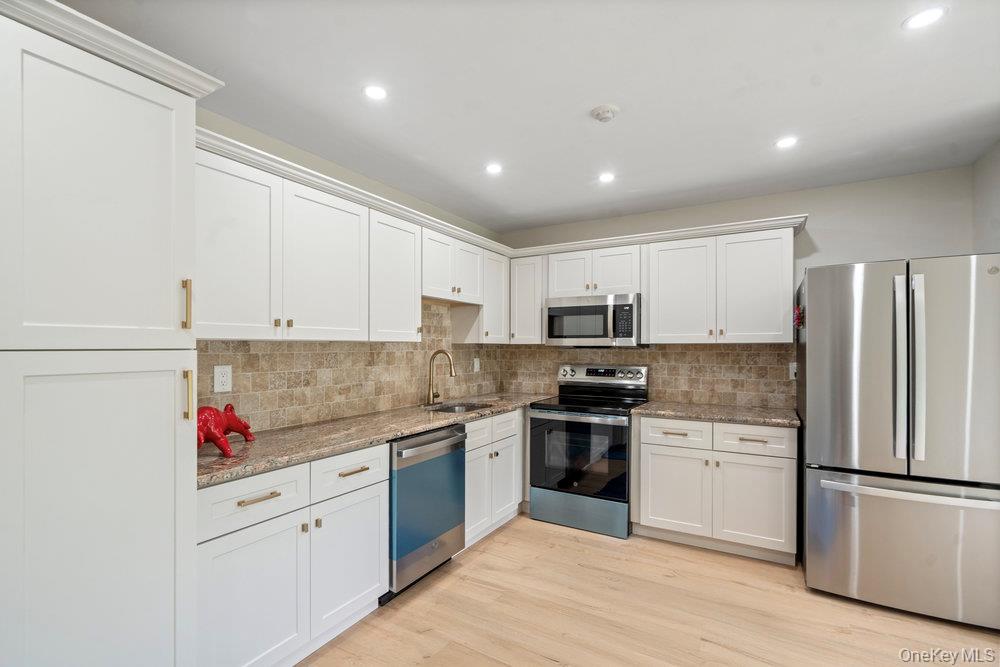 53 Freedom Lane Coram, NY 11784 - Photo 7 of 29 a kitchen with granite countertop stainless steel appliances and white cabinets