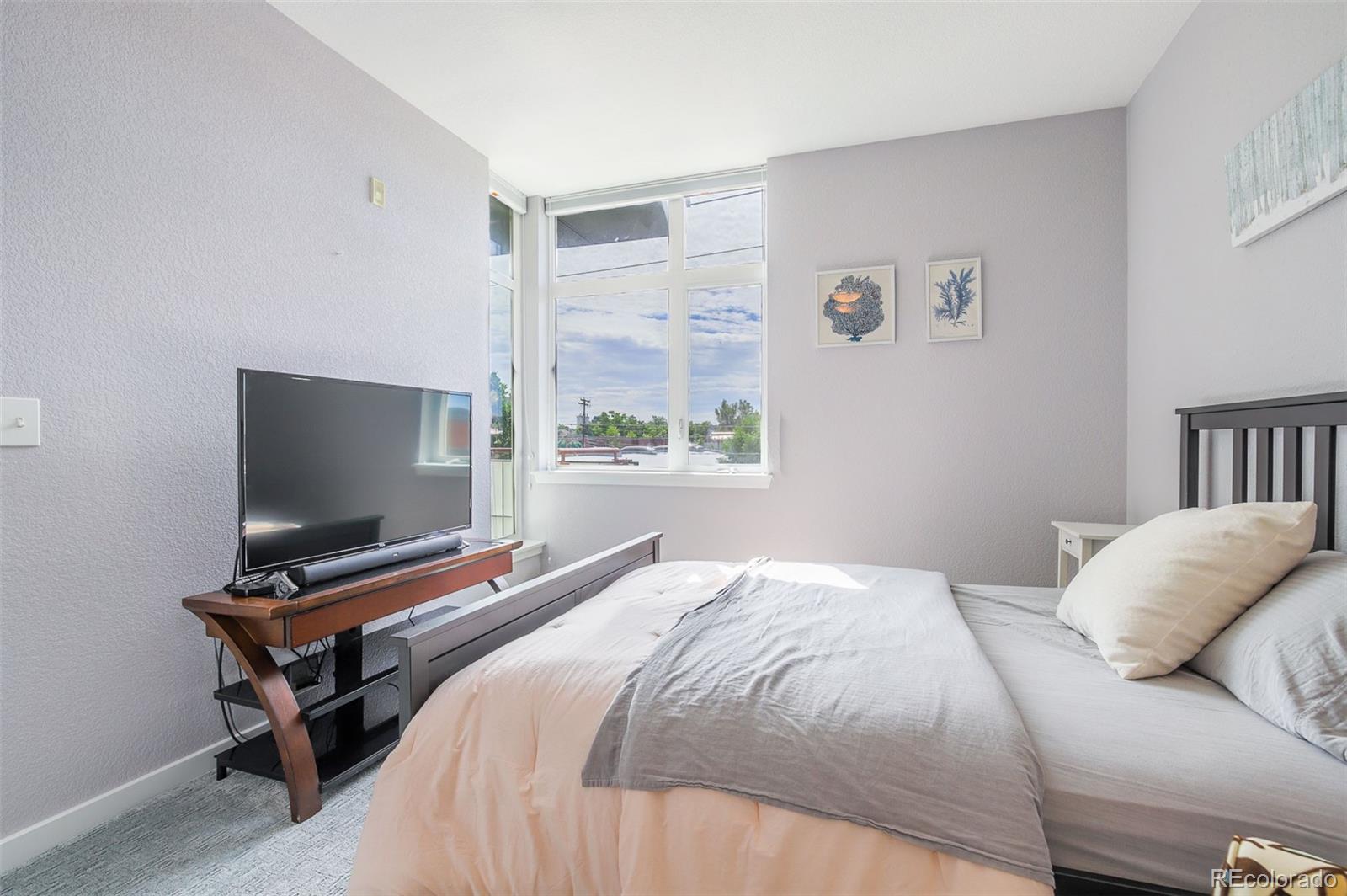 3101 Blake Street, Unit 305 Denver, CO 80205 - Photo 11 of 28 a bedroom with a bed and a flat screen tv
