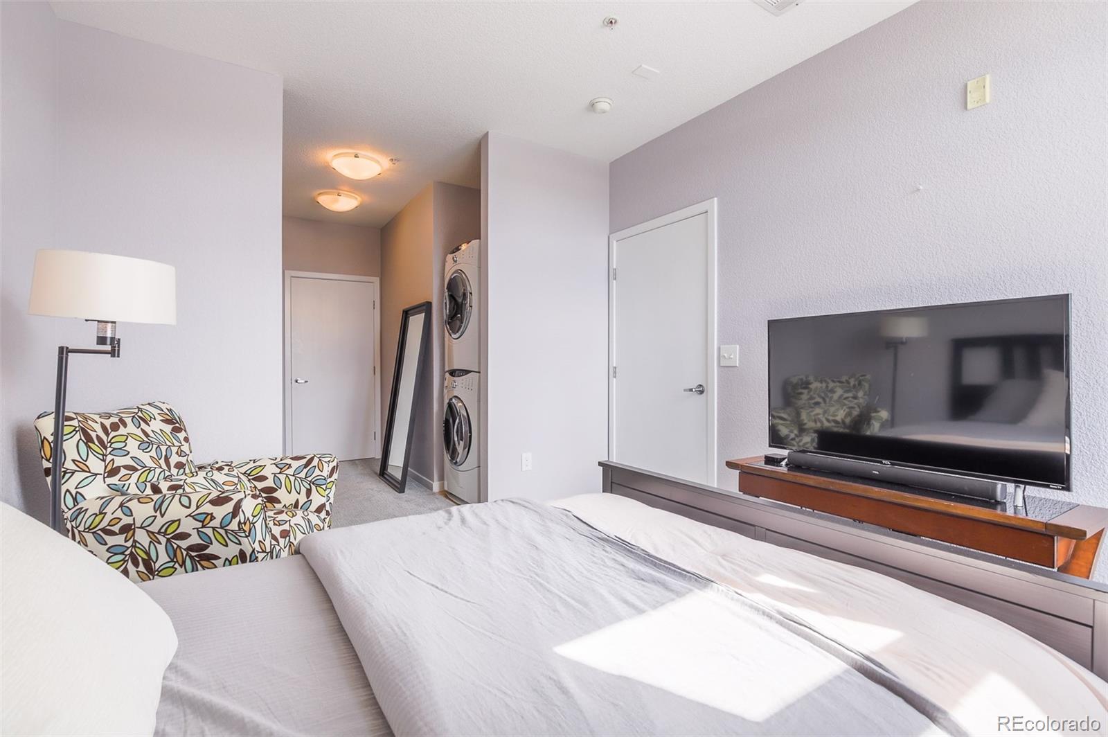 3101 Blake Street, Unit 305 Denver, CO 80205 - Photo 13 of 28 a bedroom with a bed and a flat screen tv