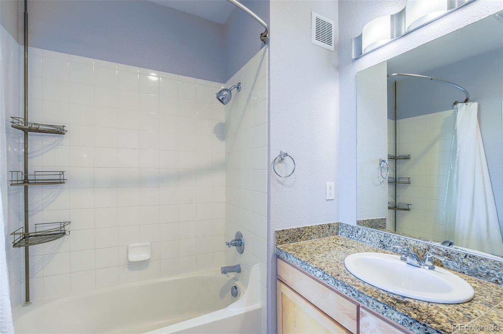 3101 Blake Street, Unit 305 Denver, CO 80205 - Photo 16 of 28 a bathroom with a granite countertop sink a mirror and a bathtub