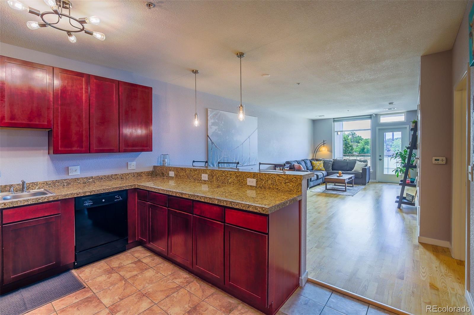 3101 Blake Street, Unit 305 Denver, CO 80205 - Photo 18 of 28 a kitchen with kitchen island granite countertop wooden floors and wooden cabinets