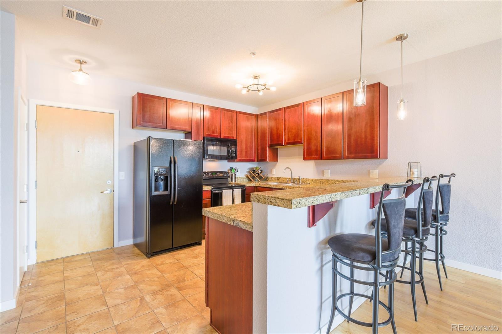 3101 Blake Street, Unit 305 Denver, CO 80205 - Photo 21 of 28 a open kitchen with stainless steel appliances granite countertop a refrigerator a sink dishwasher a stove with chairs and white cabinets