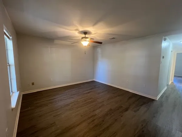 an empty room with wooden floor and fan