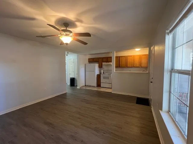 an empty room with wooden floor fan and windows