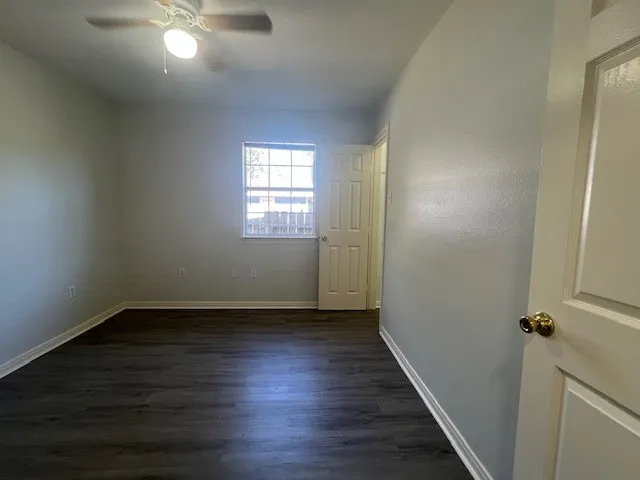 a view of an empty room with window and wooden floor