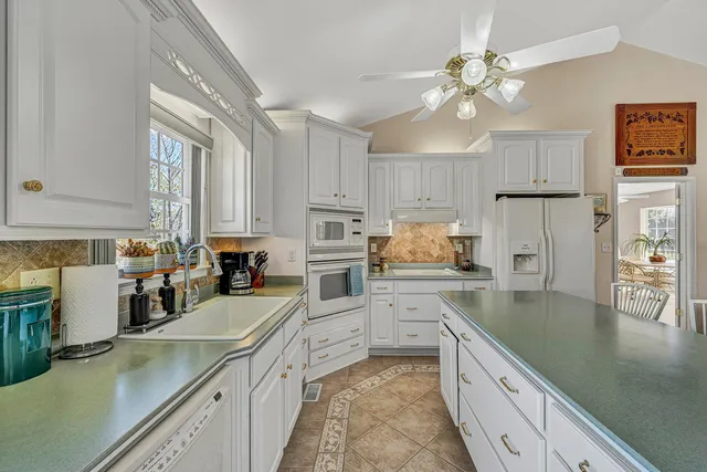 a kitchen with stainless steel appliances granite countertop a refrigerator a stove a kitchen island with a stove and white cabinets