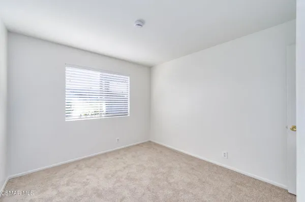 a view of an empty room with closet and a window