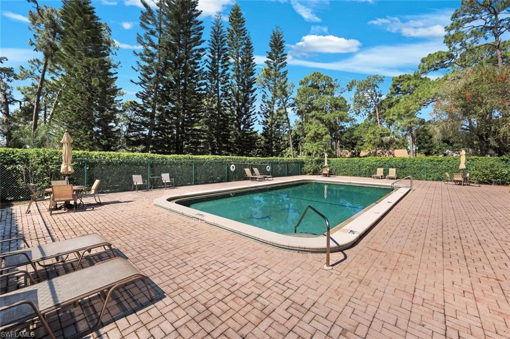 5857 Rattlesnake Hammock Road, Unit 101 Naples, FL 34113 - Photo 18 of 19 Outdoor swimming pool with integrated steps, surrounded by a paver patio and mature landscaping