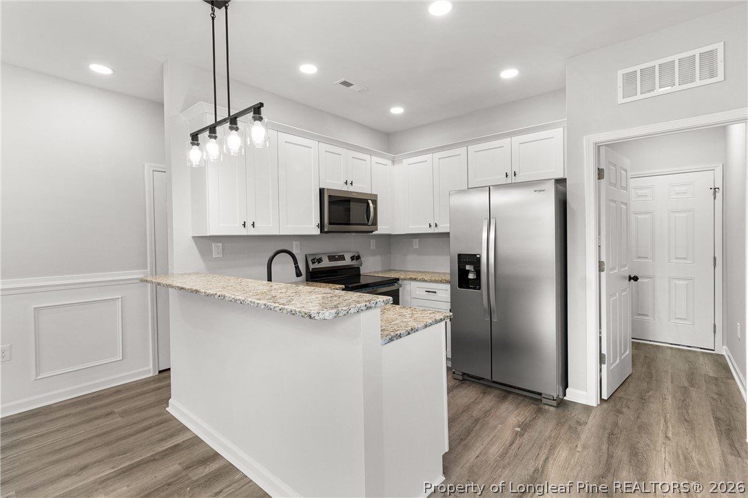 802 Holmes Street Clinton, NC 28328 - Photo 8 of 31 a kitchen with kitchen island granite countertop a refrigerator a sink dishwasher a stove and white cabinets with wooden floor