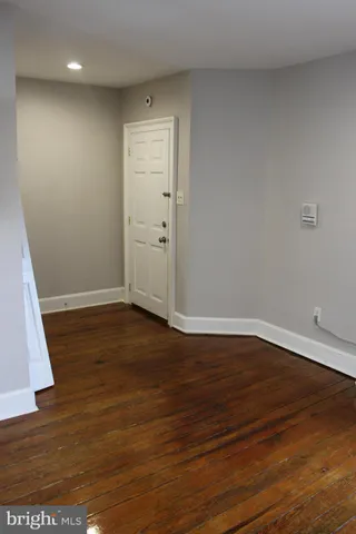a view of an empty room with wooden floor and closet