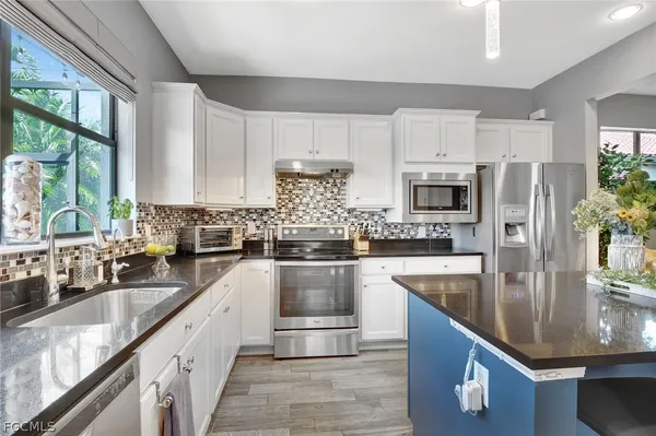 a kitchen with stainless steel appliances granite countertop a sink a stove and a refrigerator