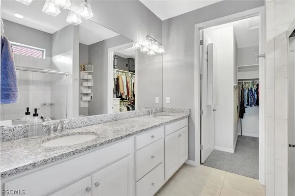 a bathroom with a granite countertop double vanity sink a mirror and a shower