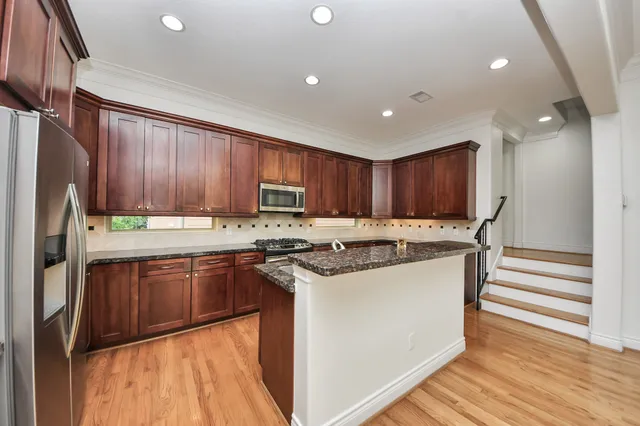 a kitchen with kitchen island granite countertop a sink stove and cabinets