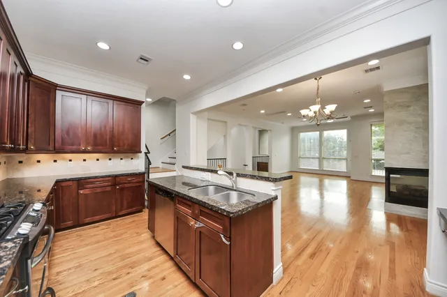 a kitchen with stainless steel appliances granite countertop wooden cabinets a stove and a sink