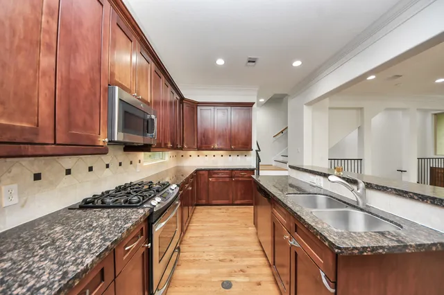 a kitchen with stainless steel appliances granite countertop a stove a refrigerator a sink and a oven