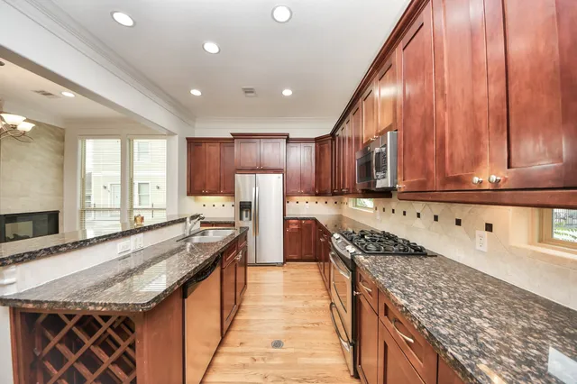 a view of a kitchen with granite countertop a sink and dishwasher stove with wooden floor