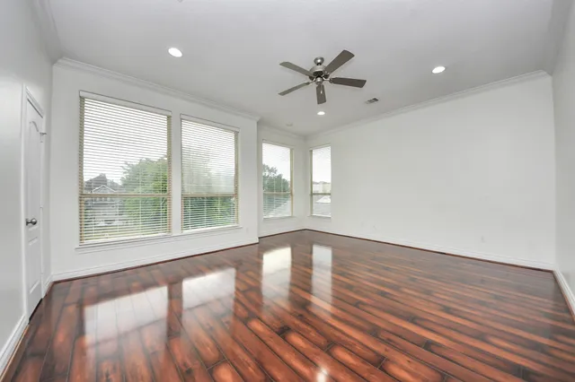 an empty room with wooden floor and windows