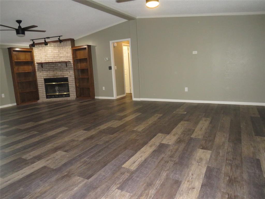 2151 Crockett Road Sanger, TX 76266 - Photo 5 of 30 an empty room with wooden floor fireplace and windows