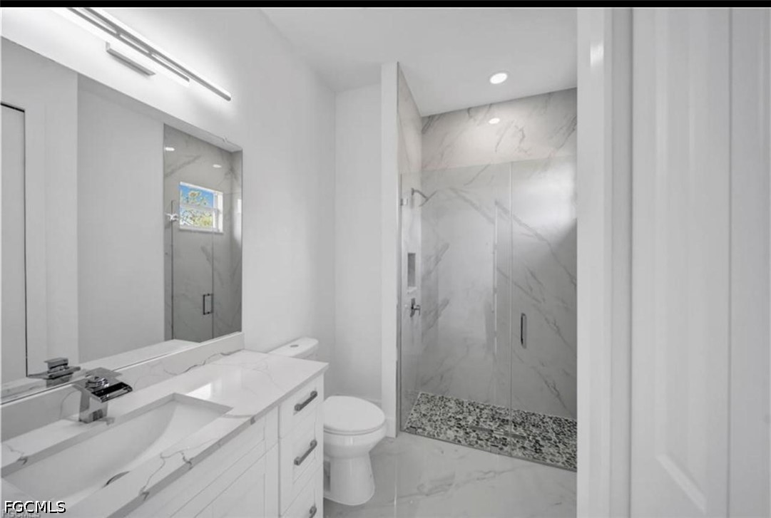 222 Pullman Street Lehigh Acres, FL 33974 - Photo 4 of 9 a bathroom with a granite countertop sink a toilet and shower