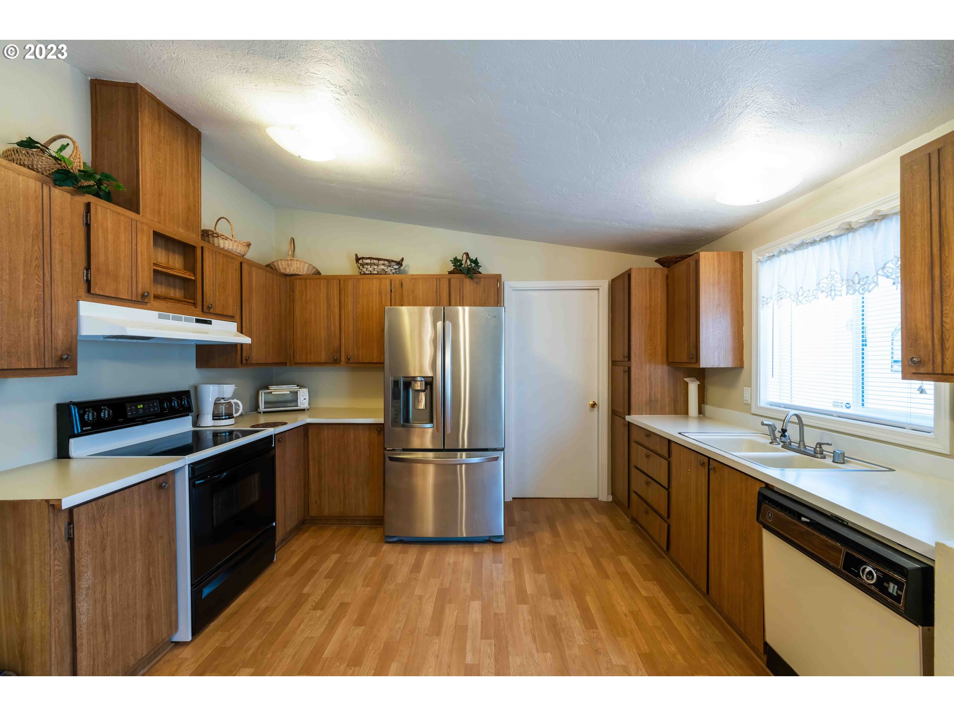 150 North 11th Street Lakeside, OR 97449 - Photo 15 of 24 a kitchen with stainless steel appliances granite countertop a refrigerator a sink dishwasher a stove and white countertops with wooden floor