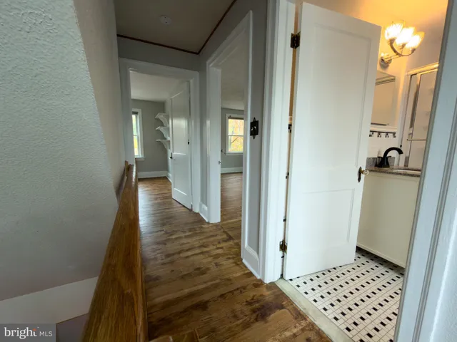 a view of a hallway with wooden floor and cabinets