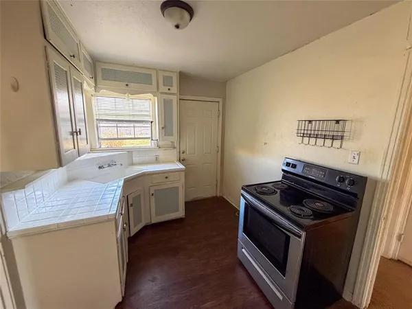 a kitchen that has a sink a stove and wooden floor