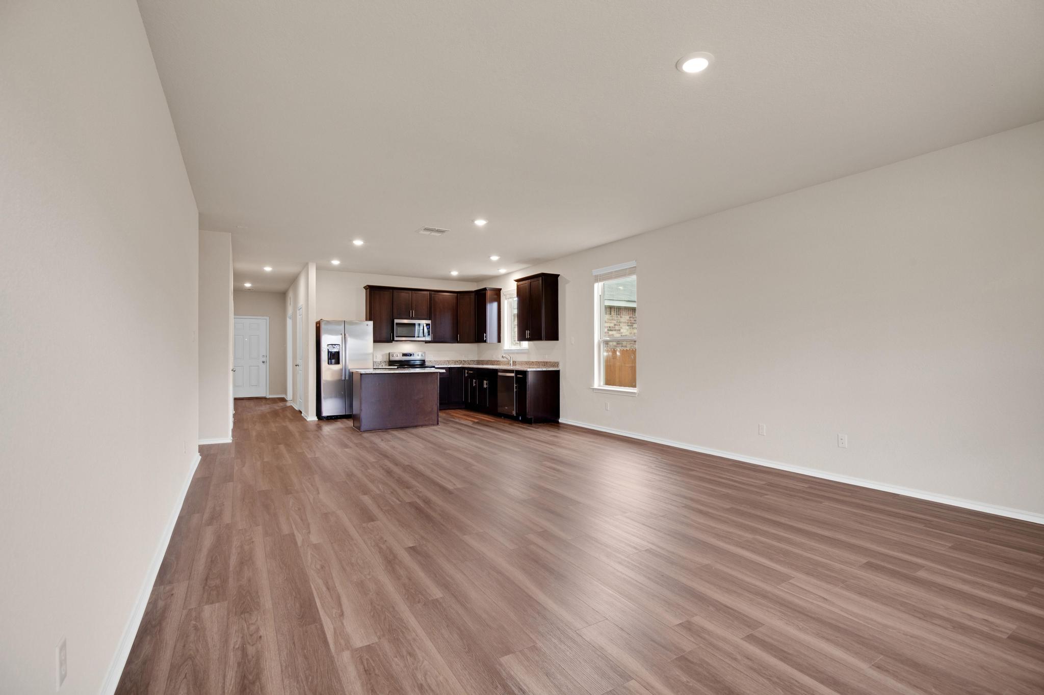 200 Janice Road Taylor, TX 76574 - Photo 4 of 25 An open-concept layout unites the kitchen and living spaces, featuring resilient laminate flooring.