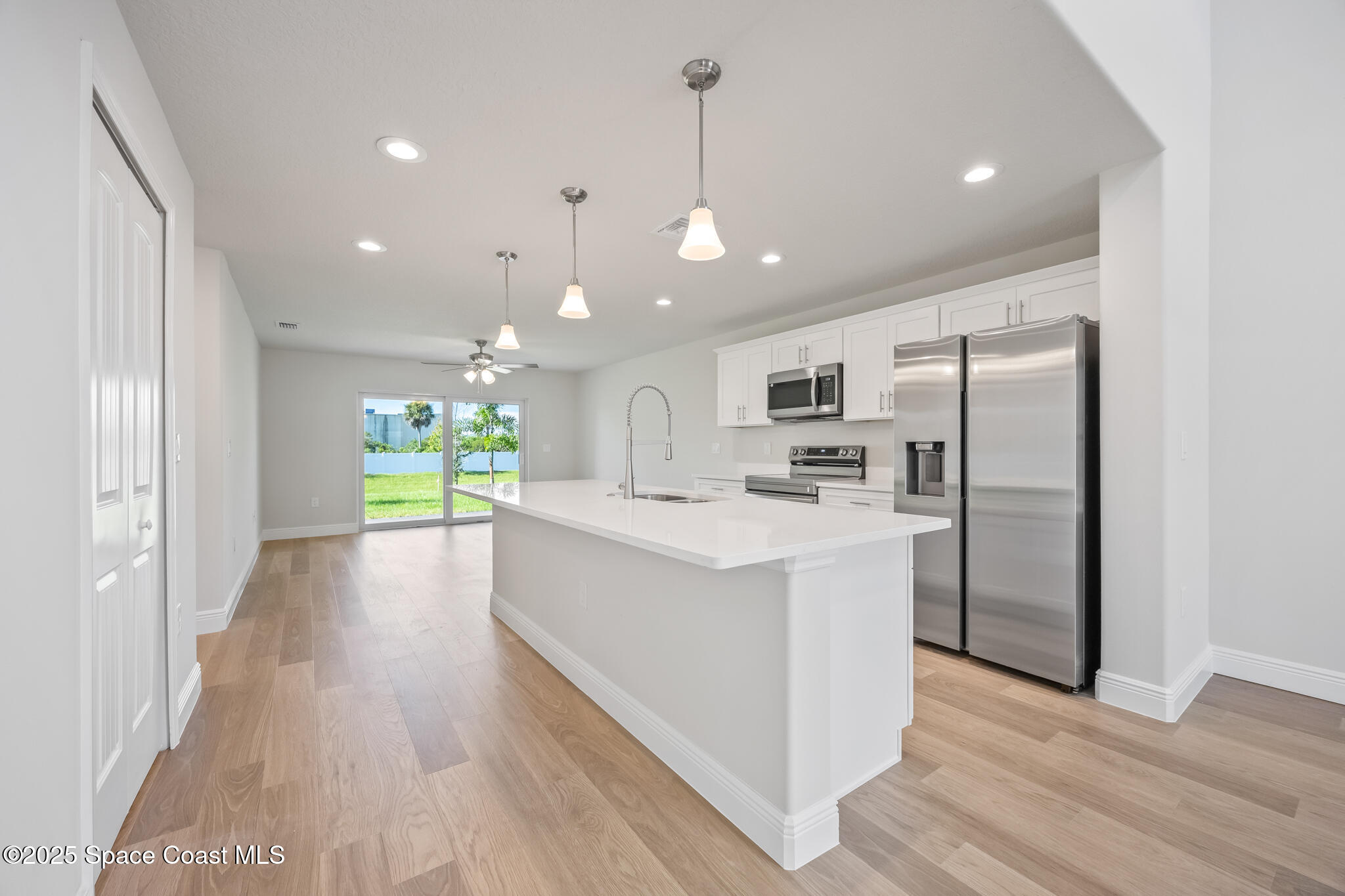 207 Hidden Woods Place Melbourne, FL 32901 - Photo 8 of 33 a kitchen with kitchen island a sink wooden floor and a refrigerator