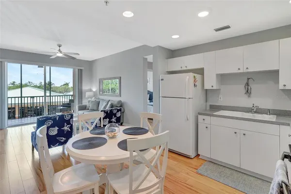 a kitchen with a sink a refrigerator and white cabinets with wooden floor
