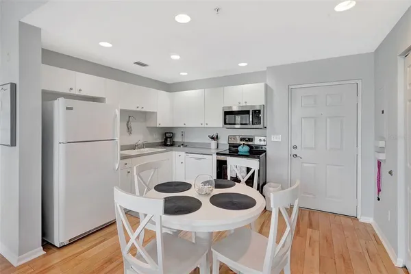 a kitchen with a refrigerator a stove a sink and a dining table with wooden floor