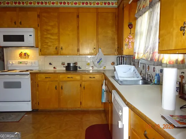 a utility room with stainless steel appliances granite countertop a sink a stove and a refrigerator