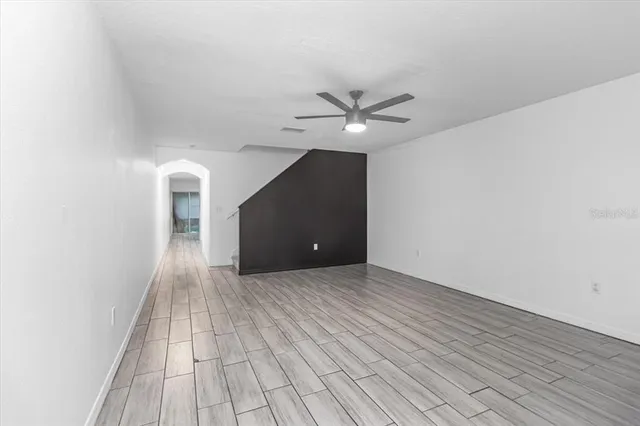 an empty room with wooden floor and ceiling fan